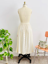 Load image into Gallery viewer, back side of a vintage 1970s white cotton embroidered skirt on mannequin
