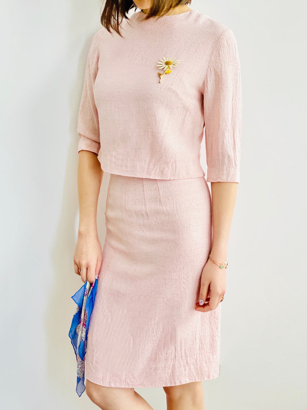 model wearing a 1940s pink linen two piece set with daisy brooch