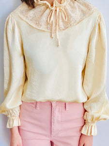 model wearing a vintage beige color satin blouse with lace ruffled collar and balloon sleeves Pink pants 