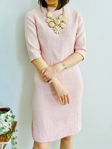model wearing a 1940s pink linen two piece set with large pearl necklace 
