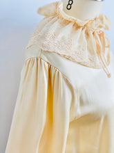 Load image into Gallery viewer, shoulder view of a mannequin display a vintage beige color satin blouse with lace ruffled collar
