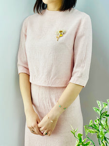 model wearing a 1940s pink linen two piece set with daisy brooch