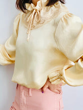Load image into Gallery viewer, model wearing a vintage beige color satin blouse with lace ruffled collar and balloon sleeves 
