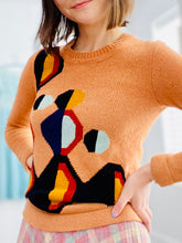 Load image into Gallery viewer, model wearing a vintage orange color sweater with art deco pattern 
