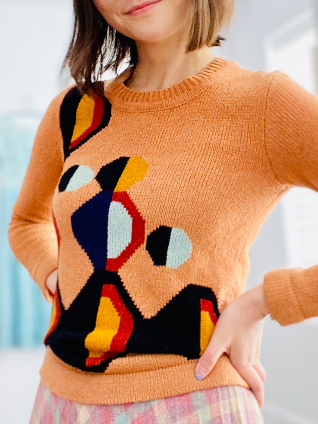 model wearing a vintage orange color sweater with art deco pattern 