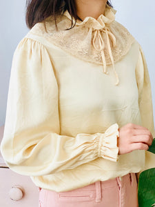 model wearing a vintage beige color satin blouse with lace ruffled collar and balloon sleeves