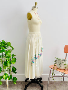 side view of a mannequin displays a vintage 1970s white cotton embroidered skirt 
